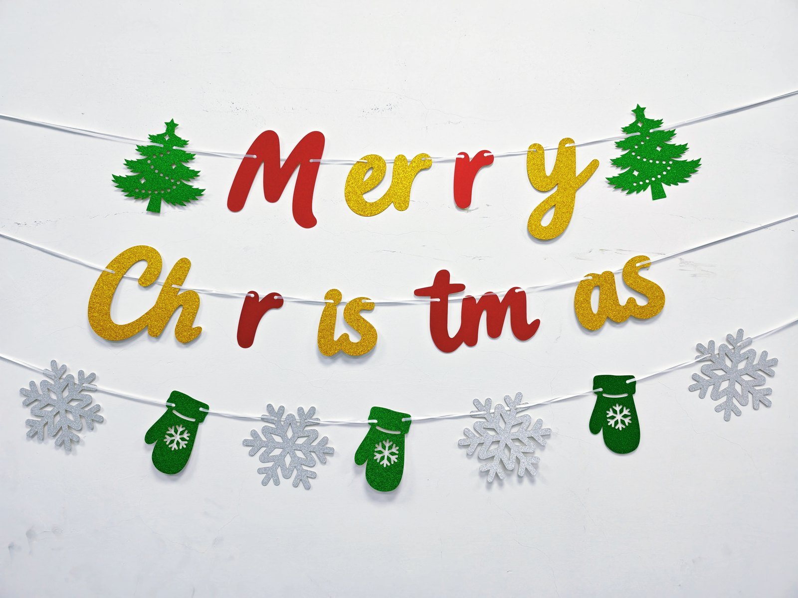 Christmas glitter banner set Style 2605 hung on a wall — Merry Christmas glitter letters with tree, snowflake and mitten motifs