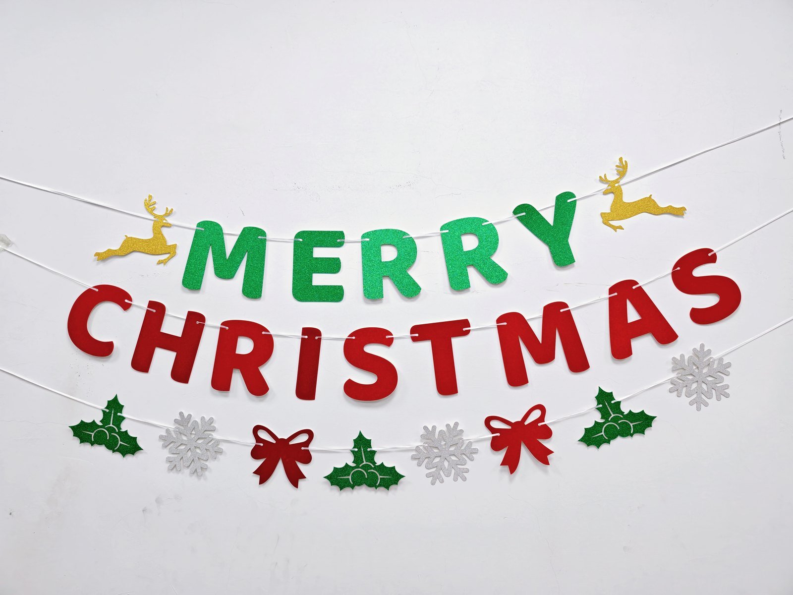 Christmas glitter banner set Style 2607 hung on a wall — green and red letter banner with reindeer, holly, bows and snowflakes